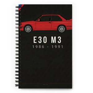 May include: A spiral-bound notebook with a black cover featuring a red car illustration. The text "E30 M3 1986 - 1991" is printed in white. The top edge has a blue, red, and white stripe design.