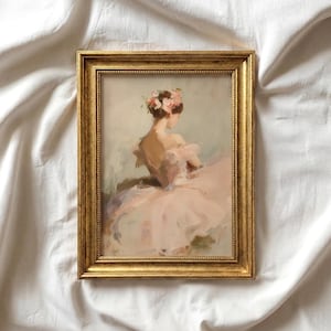 May include: A rectangular gold-toned frame containing an impressionistic painting of a figure viewed from behind. The subject wears a pale pink dress and has a cluster of pink flowers in their hair, set against a soft, muted, light-colored background.