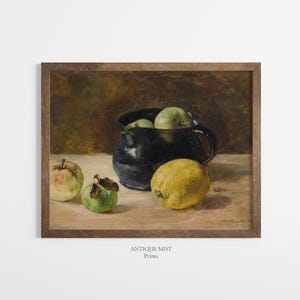 May include: A framed oil painting print featuring a dark blue ceramic pitcher filled with green apples, placed on a light surface alongside a large yellow lemon and two additional green apples. The text "ANTIQUE MIST Prints" appears below.