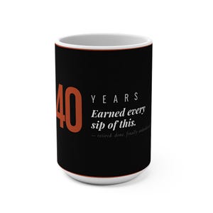 May include: A white ceramic coffee mug with a black exterior. The mug features the number "40" in orange, the word "YEARS", and the text "Earned every sip of this." in white. The mug is a retirement-themed gift.
