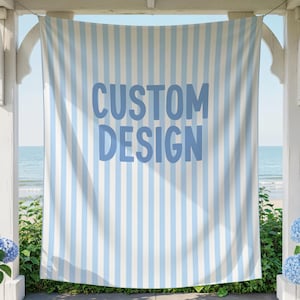 May include: A rectangular fabric banner featuring a vertical light blue and white striped pattern. The text CUSTOM DESIGN is printed in large, bold, light blue sans-serif capital letters across the center of the striped fabric surface.
