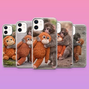 May include: A collection of phone cases featuring images of monkeys hugging plush toy monkeys. The cases are clear with a glossy finish, showcasing the colorful images. The plush toys are orange and brown, and the monkeys are gray.