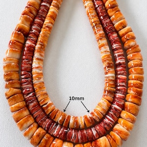 May include: Three strands of disc-shaped beads in shades of orange, red, and white. The beads on the inner strand are labeled as 10mm in diameter, while the beads on the outer strand are labeled as 14mm in diameter. The beads have a smooth, polished finish.