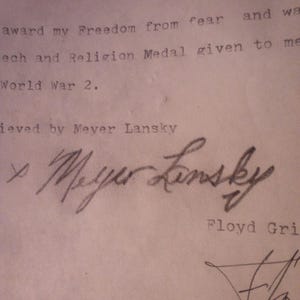 Puede incluir: Primer plano de un documento con texto mecanografiado y firmas manuscritas. El documento menciona "Libertad del miedo" y "Segunda Guerra Mundial". La firma "Meyer Lansky" es visible, junto con otra firma.