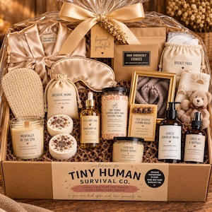 May include: A gift basket containing a champagne-colored satin robe and eye mask, a candle labeled Mentally at the Spa, shower steamers, body oil, bath soak, body scrub, perineal wash, magnesium spray, breast pads, and a small teddy bear.