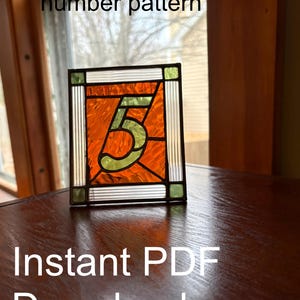 Puede incluir: Un patrón de número de mesa de vidriera, de aproximadamente 11,4 cm x 14 cm, que muestra el número 5 en naranja y verde. El diseño está enmarcado con detalles en blanco y verde. El texto "Instant PDF Download" es visible en la parte inferior.