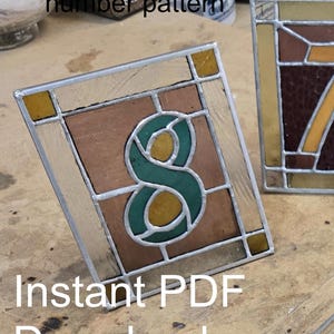 May include: A stained glass table number pattern, featuring the number 8 in green and yellow, set against a brown background. The glass is framed with a silver border. The dimensions are 4.5" x 5.5". The text "Instant PDF Download" is visible.