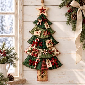 Puede incluir: Un tapiz de pared de tela acolchada con forma de árbol de Navidad, con patrones de cuadros verdes y rojos, decorado con pequeños adornos de tela que incluyen bastones de caramelo, cajas de regalo, etiquetas y una estrella en la punta.