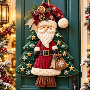 Può includere: Una decorazione da parete in tessuto trapuntato a forma di albero di Natale con una figura di Babbo Natale al centro. Babbo Natale indossa un cappotto e un cappello rossi con bordi bianchi e tiene un piccolo sacco color cuoio. L'albero è verde.
