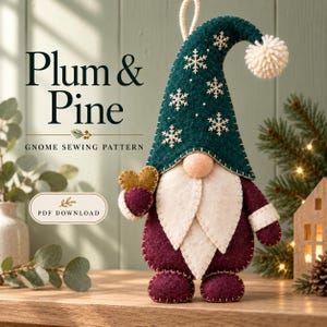 Puede incluir: Un adorno de gnomo de fieltro con un sombrero verde oscuro con copos de nieve blancos bordados y un pompón blanco, una barba color crema y un cuerpo color ciruela. El gnomo sostiene un corazón dorado. Texto: Plum & Pine Gnome Sewing Pattern.