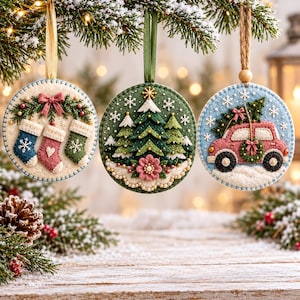 May include: Three circular felt ornaments hanging from ribbons. The left ornament features three stockings and a bow. The centre ornament displays three pine trees and a flower. The right ornament shows a pink car carrying a tree with a wreath.