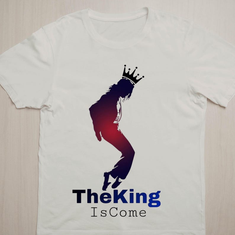 May include: White t-shirt featuring a silhouette of a person wearing a crown, in a dance pose. The silhouette is shaded in red and blue. The text "The King Is Come" is printed below the silhouette in black and blue.