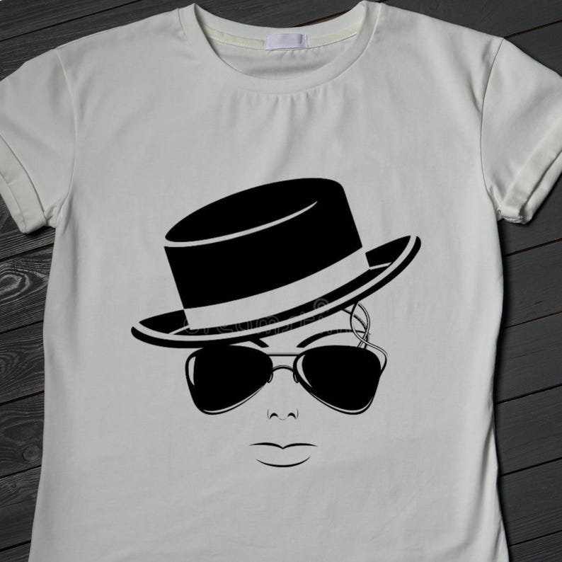 May include: A white t-shirt featuring a black and white graphic of a face wearing a fedora hat and sunglasses. The design is a minimalist illustration, with clean lines and a modern aesthetic. The shirt is made of a soft, comfortable material.
