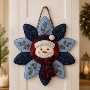 Peut inclure: Une décoration murale en tissu matelassé en forme d'étoile avec un visage de bonhomme de neige au centre. Le bonhomme de neige porte un bonnet en tricot crème et une écharpe à carreaux rouge et bleu marine. Les pétales présentent des motifs brodés.