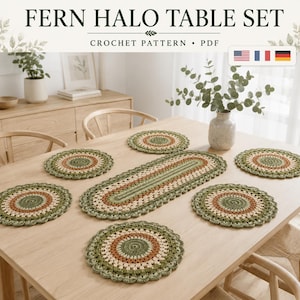 Op de afbeelding: Een haakpatroon PDF getiteld FERN HALO TABLE SET met een centrale ovale tafelloper en zes ronde placemats. De items zijn gemaakt in concentrische ringen van saliegroen, crème en terracotta garen met een geschulpte rand.