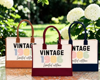 May include: Three rectangular canvas tote bags with two handles each. The bags feature the text VINTAGE, the year 1986, and the words Limited edition. The left bag has a brown base, the center bag has a maroon base, and the right bag has a navy base.
