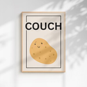 Puede incluir: Un cuadro enmarcado con una ilustración de una patata de dibujos animados con una cara sonriente. La palabra "COUCH" está impresa en negro encima de la patata. La impresión tiene un fondo beige claro y un marco de madera.