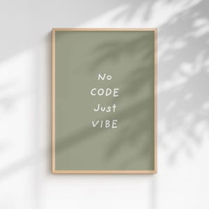 Może przedstawiać: Oprawiony wydruk z napisem "No CODE Just VIBE" białymi literami na szałwiowym zielonym tle. Rama ma jasny kolor drewna. Wydruk jest wyświetlany na białej ścianie z cieniami.