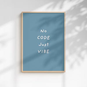 Peut inclure: Impression d'art encadrée avec un cadre en bois clair. L'œuvre présente les mots "No CODE Just VIBE" en blanc, centrés sur un fond bleu uni. L'impression est affichée contre un mur blanc avec des ombres.