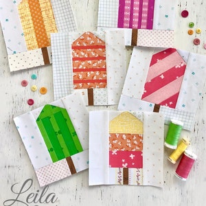 Pu&ograve; includere: Sei blocchi di patchwork a forma di ghiacciolo da 15 cm, realizzati con fondazioni di carta. I blocchi presentano una variet&agrave; di tessuti colorati con diversi motivi, tra cui strisce, pois e stampe floreali. I blocchi sono disposti su una superficie di legno bianco con bottoni e bobine di filo.