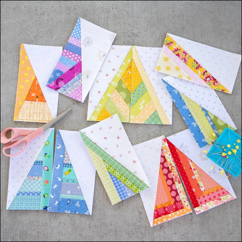 May include: Nine colorful fabric triangles with a white background. Each triangle is made of strips of fabric in different colors and patterns. The triangles are arranged in a staggered pattern on a gray surface.