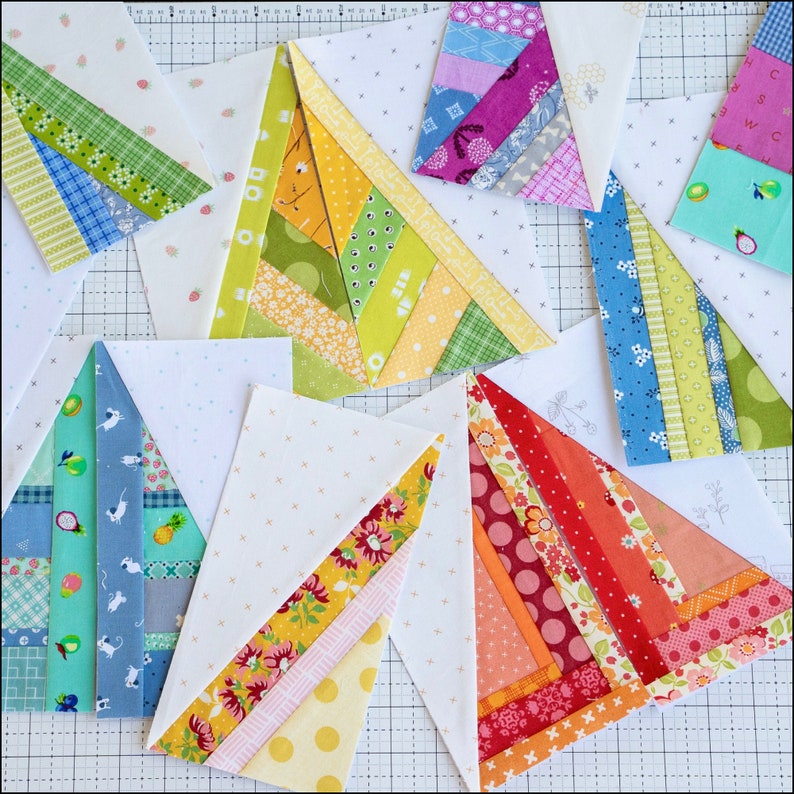 May include: A collection of nine unfinished patchwork quilt blocks in various colors and patterns, including red, orange, yellow, green, blue, and purple. Each block is a triangle shape with a white background and a diagonal line of fabric strips.