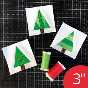 May include: Three square fabric quilt blocks featuring pieced green tree designs with brown trunks on white backgrounds, accompanied by one spool of light green thread and one spool of red thread, all measuring 3 inches in size.