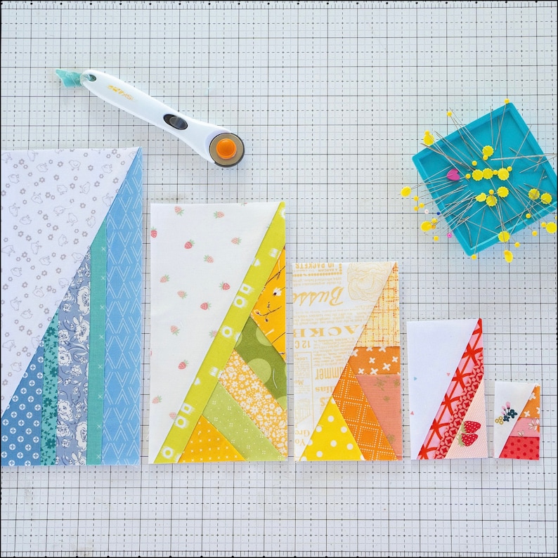 May include: Five fabric squares with different patterns and colors, including white, blue, green, yellow, orange, and pink. The squares are arranged in a row on a white gridded surface.