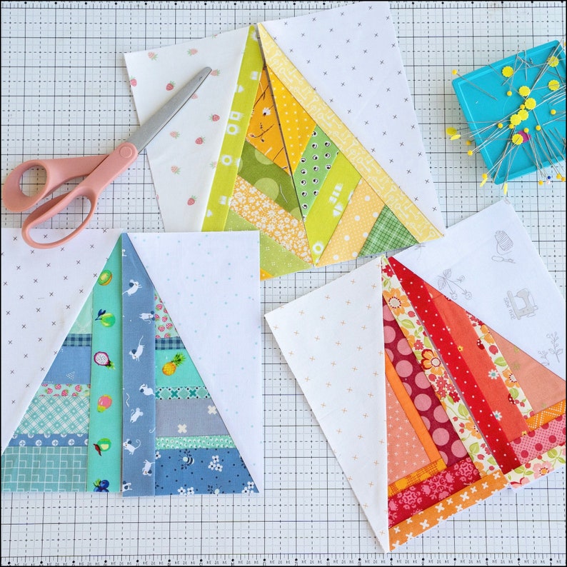 May include: Three unfinished quilt blocks in the shape of a triangle. The blocks are made of strips of fabric in various colors and patterns. The blocks are on a white gridded surface.