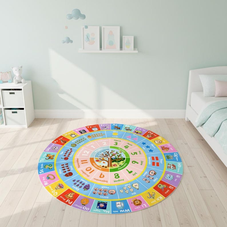 May include: A round educational area rug featuring a colorful alphabet border with corresponding illustrations, a central calendar with months and numbers, and a seasonal tree graphic in the middle, all set against a light-colored wooden floor.