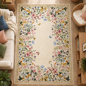 May include: A rectangular area rug with a cream-colored center featuring a border of colorful wildflowers, green leaves, and small butterflies. The rug has a decorative tan frame with a repeating leaf pattern along the outer edges of the design.
