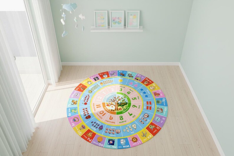 May include: A round educational area rug featuring a colorful design with the alphabet, numbers one through twelve, months of the year, and illustrations of various objects, animals, and fruits arranged in concentric circles on a light background.