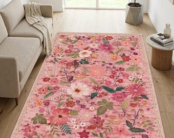 May include: A rectangular area rug featuring a pink background with a dense, multi-colored floral pattern. The design includes various flowers, leaves, and stems in shades of red, orange, yellow, green, and white, finished with a decorative border.