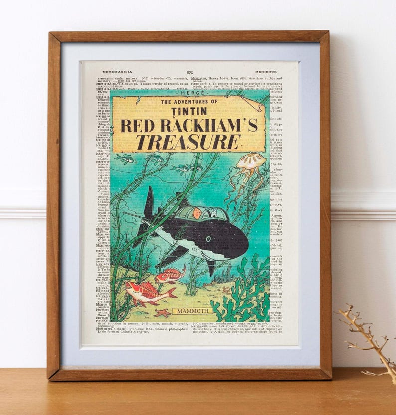 May include: Framed print of a vintage comic book cover, "The Adventures of Tintin: Red Rackham's Treasure." The artwork depicts a submarine shaped like a shark underwater, with fish and seaweed. The background is a dictionary page.