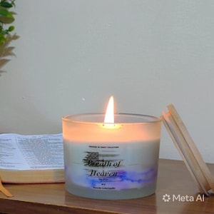 Può includere: Una candela di cera di soia accesa in un barattolo di vetro trasparente con coperchio in legno. L'etichetta presenta una bandiera americana invecchiata e il testo "Freedom in Christ Collection", "Breath of Heaven", "Soy Wax" e "16 oz". Un libro è visibile.