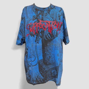 Könnte beinhalten: Blau-schwarzes Grafik-T-Shirt mit dem Wort "Suffocation" in Rot. Das Shirt hat einen Allover-Print mit einem detaillierten, abstrakten Design. Das T-Shirt hat kurze Ärmel und einen Rundhalsausschnitt.