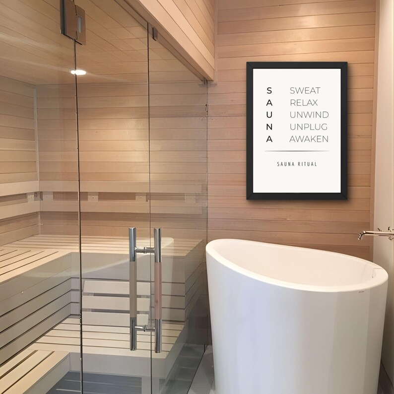 May include: A modern bathroom with a sauna and a white bathtub. A framed print on the wall reads "SAUNA" vertically, with related words beside each letter. The sauna has glass doors and light wood paneling. The bathtub is a curved, freestanding design.