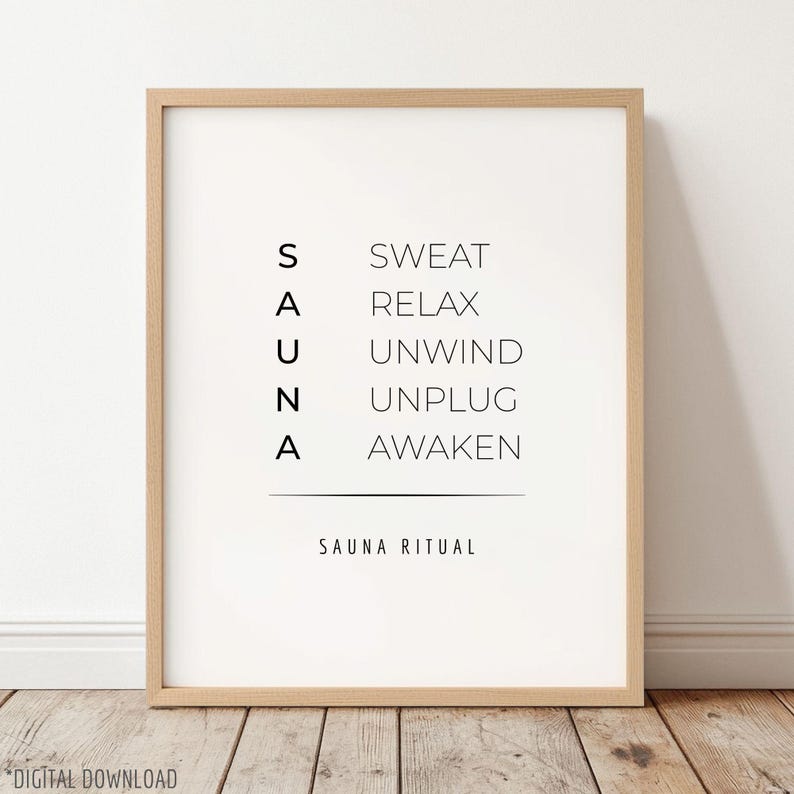 May include: A framed print with the word "SAUNA" vertically aligned on the left, and related words on the right: SWEAT, RELAX, UNWIND, UNPLUG, AWAKEN. Below, the text "SAUNA RITUAL" is displayed. The frame is a light brown color.