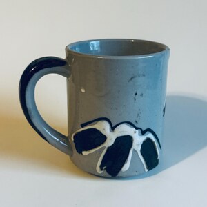 Puede incluir: Un juego de tres tazas de cerámica con un acabado mate moteado. Las tazas son de color crema, azul claro y gris. Cada taza tiene un diseño simple y moderno, ideal para café o té.