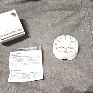 Può includere: Una tazza di ceramica bianca con manico nero e la scritta "But First, Coffee" in nero, in grassetto. La tazza è su una superficie bianca.