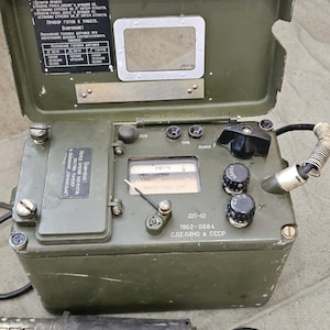 Peut inclure: Un détecteur de rayonnement DP-12 vert olive avec un dessus articulé, des cadrans et un compteur. L'appareil a une sonde attachée et du texte en russe. L'appareil date de 1962 et est fabriqué en URSS.