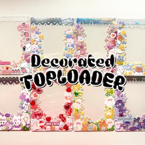 May include: A collection of decorated toploaders with various colorful designs. Each toploader features a clear plastic frame adorned with stickers of cute characters, hearts, stars, and other decorative elements. The text "Decorated TOPLOADER" is displayed in the center.