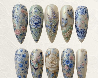 May include: A set of ten almond-shaped artificial nails. Each nail features intricate floral and butterfly designs in shades of blue, pink, and gold on a pearlescent base. The designs include roses, butterflies, and detailed patterns.