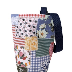 May include: A patchwork tote bag with a blue and white floral pattern, red and white stripes, and a blue gingham pattern. The bag has a navy blue strap.