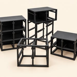 May include: A collection of four black modular storage units with open-frame designs. Each unit features a rectangular structure with internal dividers and cross-braced supports, constructed from matte black material with visible joinery.