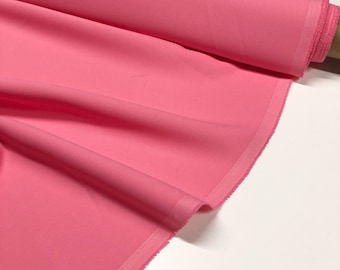 May include: A roll of pink fabric with a smooth texture. The fabric is folded and has a white edge.