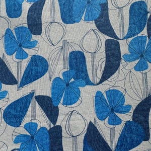 May include: A light gray fabric featuring a repeating pattern of blue flowers and dark blue leaves. The design includes both solid blue shapes and thin dark blue line art outlines of flower buds and stems, creating a layered botanical print.