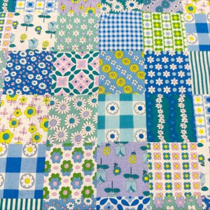 May include: A patchwork quilt featuring a variety of floral and geometric patterns in shades of blue, green, yellow, and purple. The quilt is composed of numerous fabric squares, each with a unique design, creating a vibrant and colorful textile.
