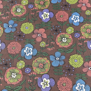 May include: A brown fabric with a repeating floral pattern. The design features various flowers in shades of blue, pink, purple, and green, with white centers and green stems. The flowers are set against a brown background.