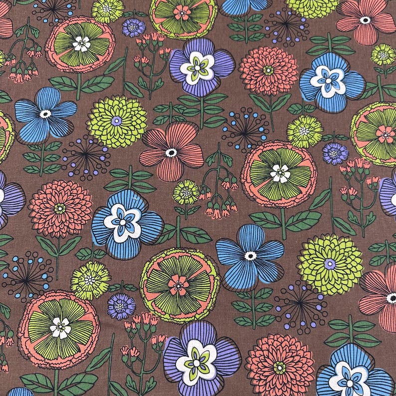 May include: A brown fabric with a repeating floral pattern. The design features various flowers in shades of blue, pink, purple, and green, with white centers and green stems. The flowers are set against a brown background.